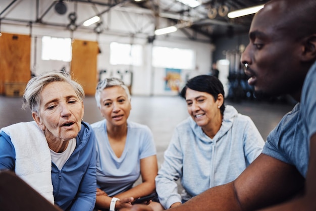 Fitness senior vrouwen en personal trainer planning gezondheidsroutine en sportschool aanmelden Ouderen en vrienden oefenen met coach man op de vloer voor training bespreken en wellness checklist of lidmaatschap