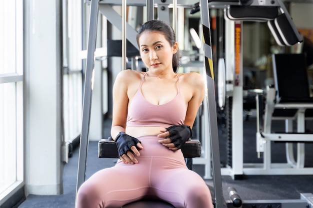 Fitness slim fit woman in sportswear sitting take a break on fitness machine in a gym room
