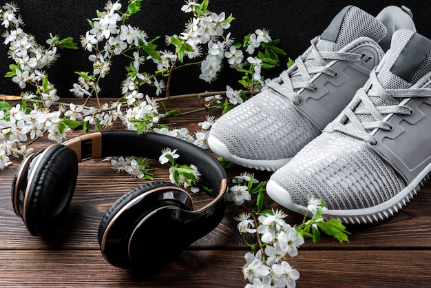 Fitness sneakers and headphones on dark wooden background.