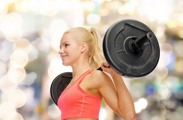 fitness, sport and dieting concept - smiling sporty woman exercising with barbell