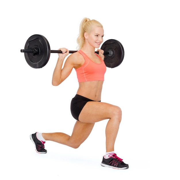 fitness, sport en bewegingsconcept - glimlachende sportieve vrouw met barbell die gesplitste squat of lunge doet