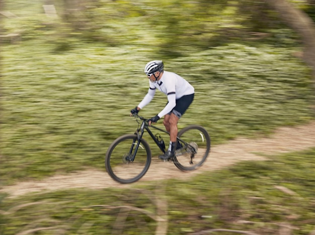 Fitness sport en man fietsen in het bos voor snelheidstraining of natuur workout met top view off road race Freedom workout en fietser op mountainbike voor extreme adrenaline of kracht prestaties