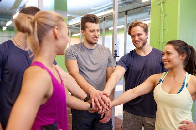 Photo fitness, sport, exercising and healthy lifestyle concept - group of happy people holding hands together in gym