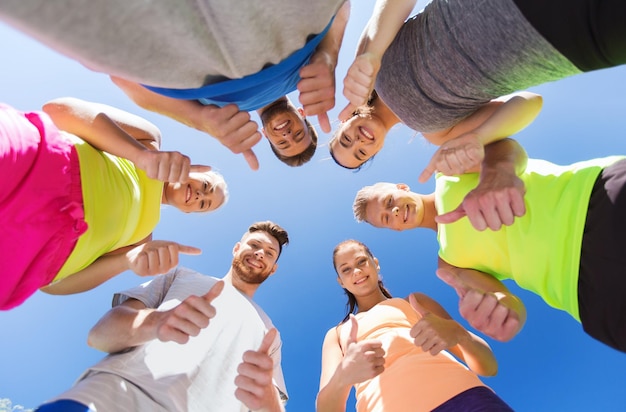 Foto concetto di fitness, sport, amicizia e stile di vita sano - gruppo di amici adolescenti felici in cerchio all'aperto che mostrano i pollici in su