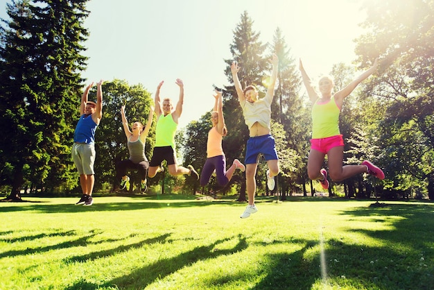 fitness, sport, friendship and healthy lifestyle concept - group of happy teenage friends jumping high outdoors