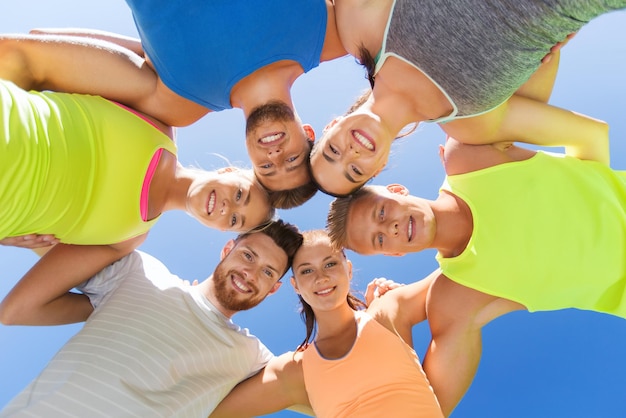 Foto concetto di fitness, sport, amicizia e stile di vita sano - gruppo di amici adolescenti felici o sportivi in cerchio all'aperto