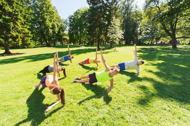 fitness, sport, friendship and healthy lifestyle concept - group of happy teenage friends or sportsmen exercising at boot camp