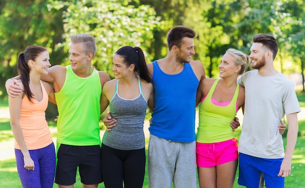 Photo fitness, sport, friendship and healthy lifestyle concept - group of happy teenage friends or sportsmen hugging and talking outdoors