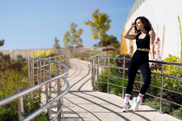 Фитнес-спортивная девушка в модной спортивной одежде позирует после фитнес-упражнений на улице