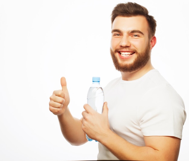 Fitness, sport  and lifestyle concept: smiling muscular sportive man wearing white shirt with bottle of water. Isolated on white.