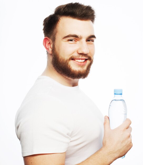 Fitness, sport  and lifestyle concept: smiling muscular sportive man wearing white shirt with bottle of water. Isolated on white.