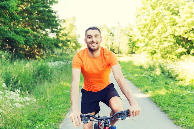 fitness, sport, mensen en een gezonde levensstijl concept - gelukkige jonge man fiets buitenshuis