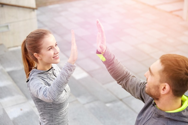 fitness, sport, mensen en gebaarconcept - glimlachend paar dat high five maakt op straat in de stad