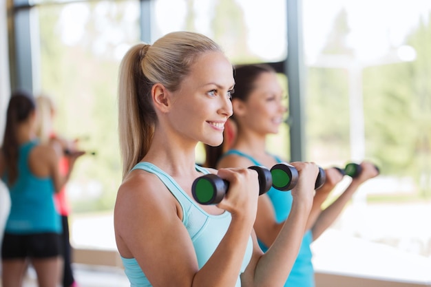 Foto fitness, sport, mensen en lifestyle concept - groep vrouwen trainen met halters in de sportschool