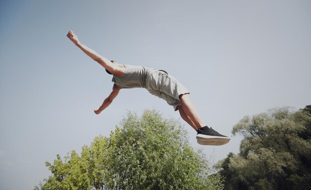 Foto fitness, sport, parkour en mensenconcept - jonge man die in het zomerpark springt