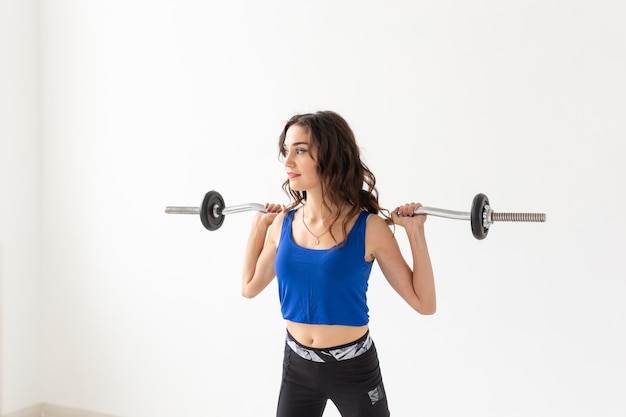 Fitness, sport and people concept - smiling sporty woman with barbell doing split squat or lunge.