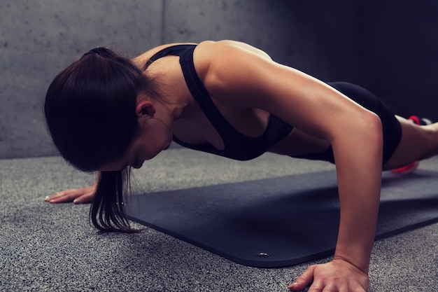 fitness, sport, people and exercising concept - woman doing push-ups in gym