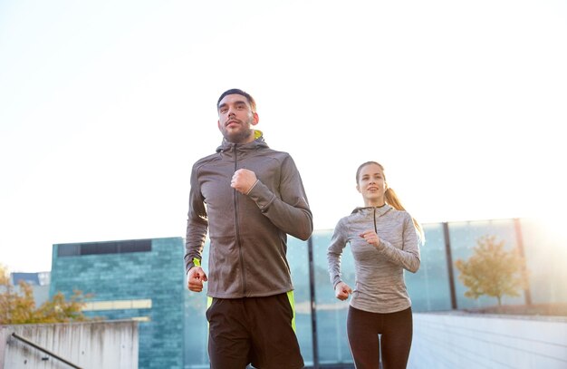 fitness, sport, people, exercising and lifestyle concept - happy couple running upstairs on city stairs