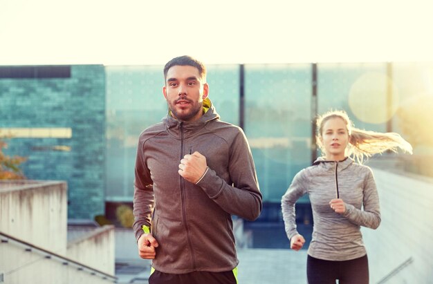 Photo fitness, sport, people, exercising and lifestyle concept - happy couple running upstairs on city stairs