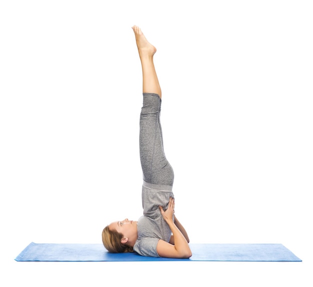 fitness, sport, people and healthy lifestyle concept - woman making yoga in shoulderstand pose on mat