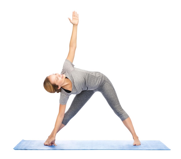 fitness, sport, people and healthy lifestyle concept - woman making yoga triangle pose on mat