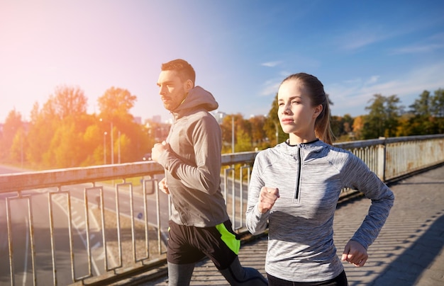 fitness, sport, people and jogging concept - happy couple running outdoors