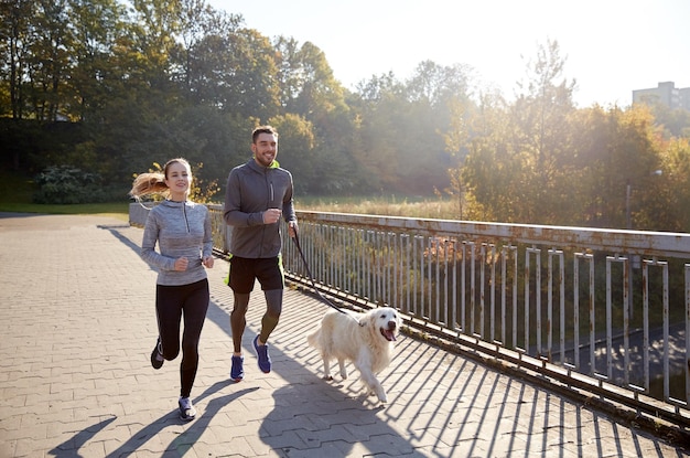 fitness, sport, people and jogging concept - happy couple with dog running outdoors