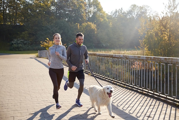 fitness, sport, people and jogging concept - happy couple with dog running outdoors