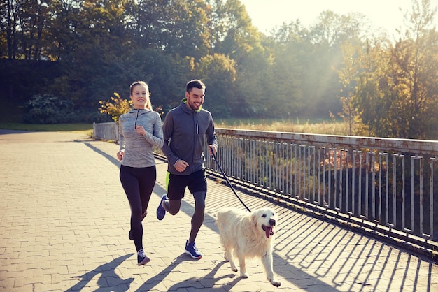 fitness, sport, people and jogging concept - happy couple with dog running outdoors