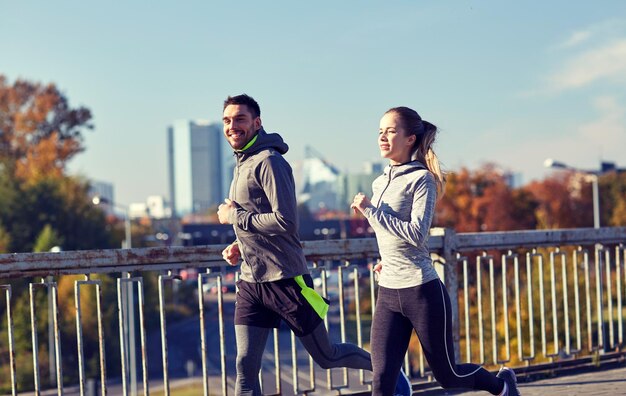 Foto concetto di fitness, sport, persone e stile di vita - coppia felice che corre all'aperto