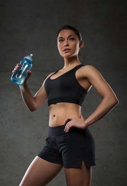 fitness, sport, training, drank en lifestyle concept - vrouw drinkwater uit de fles in de sportschool