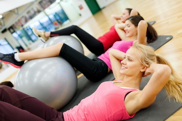 fitness, sport, training, gym en lifestyle concept - groep lachende mensen die trainen in pilatesles