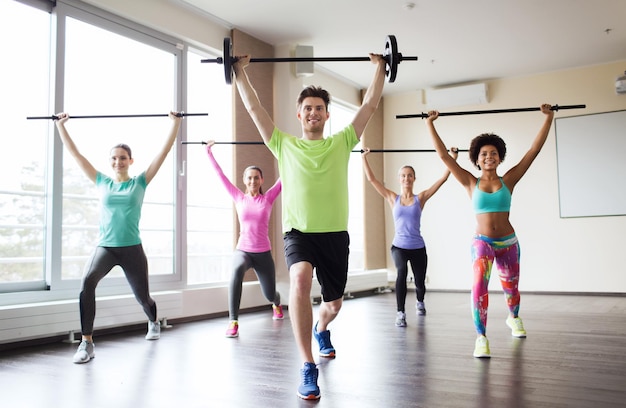 fitness, sport, training, gym and lifestyle concept - group of people exercising with bars in gym