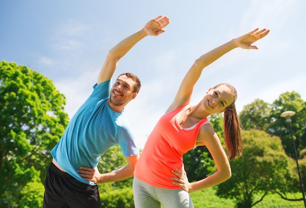 fitness, sport, training and lifestyle concept - smiling couple stretching outdoors