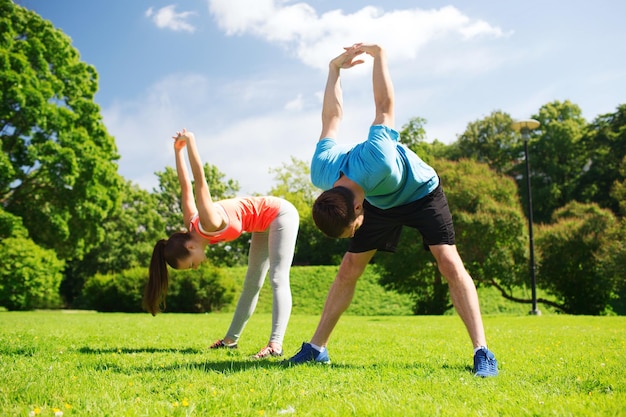 fitness, sport, training and lifestyle concept - smiling couple stretching outdoors