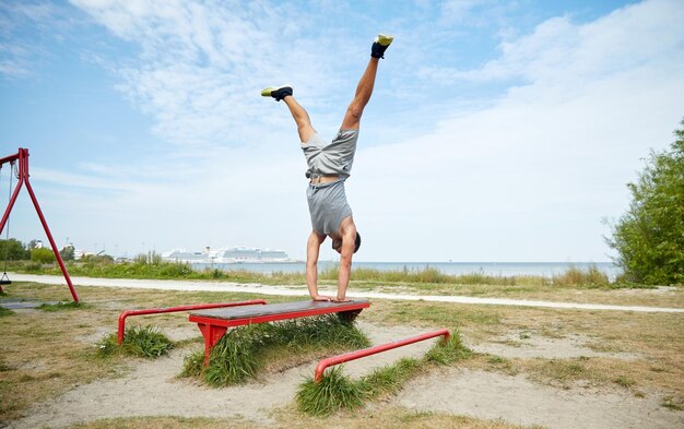 Foto concetto di fitness, sport, formazione e stile di vita - giovane che si esercita sulla panchina all'aperto