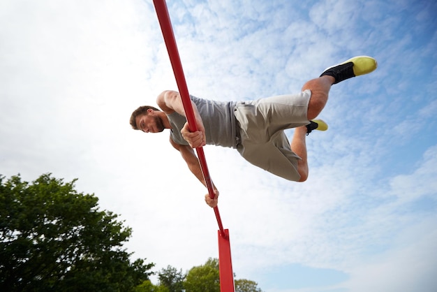 피트니스, 스포츠, 훈련 및 라이프스타일 개념 - 야외에서 수평 막대에서 운동하는 젊은 남자