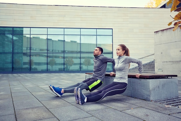 fitness, sport, training, mensen en lifestyle concept - paar doet triceps dip oefening op bankje buiten