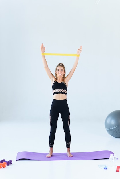 Fitness, sport, training, people and lifestyle concept - woman doing exercises with expander or resistance band in gym