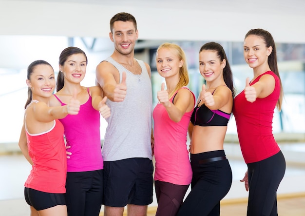 fitness, sport, training, sportschool en lifestyle concept - groep gelukkige mensen in de sportschool duimen opdagen