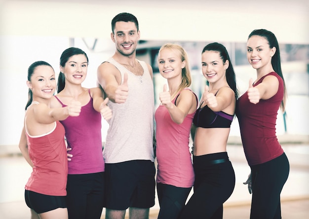 fitness, sport, training, sportschool en lifestyle concept - groep gelukkige mensen in de sportschool duimen opdagen