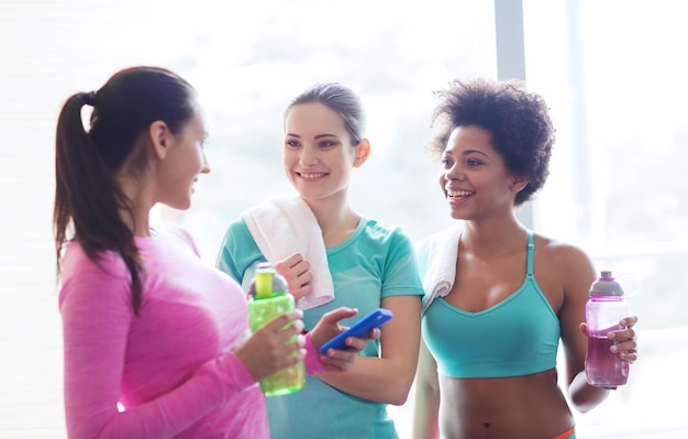 fitness, sport, training, sportschool en lifestyle concept - groep gelukkige vrouwen met flessen water in de sportschool
