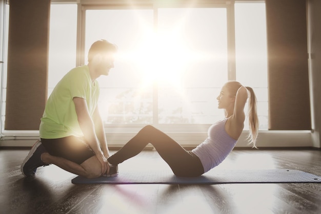 fitness, sport, training, teamwork and people concept - woman with personal trainer doing sit ups in gym