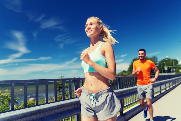 fitness, sport, vriendschap en gezond levensstijlconcept - glimlachend paar dat bij de zomerkust loopt