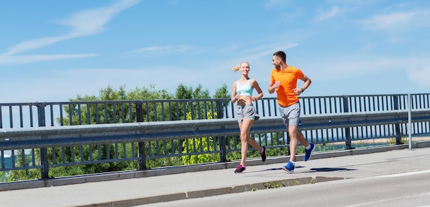 fitness, sport, vriendschap en gezond levensstijlconcept - glimlachend paar dat bij de zomerkust loopt