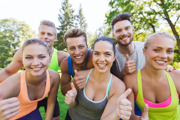 fitness, sport, vriendschap en gezond levensstijlconcept - groep gelukkige tienervrienden die buitenshuis duimen