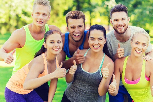 fitness, sport, vriendschap en gezond levensstijlconcept - groep gelukkige tienervrienden of sporters die buitenshuis duimen