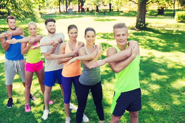 fitness, sport, vriendschap en gezond levensstijlconcept - groep gelukkige tienervrienden of sporters die oefenen en handen strekken tijdens bootcamp