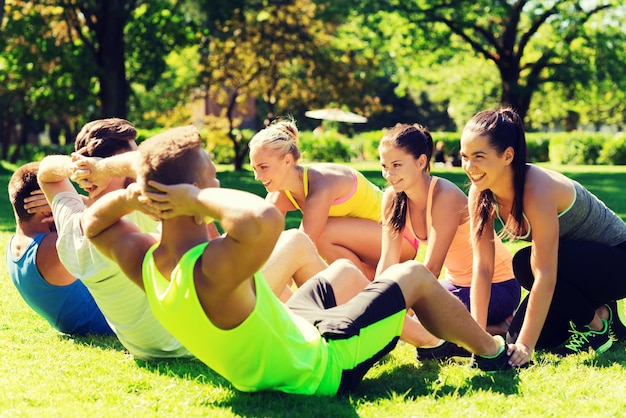 fitness, sport, vriendschap en gezond levensstijlconcept - groep gelukkige tienervrienden of sporters die oefenen en sit-ups doen tijdens bootcamp