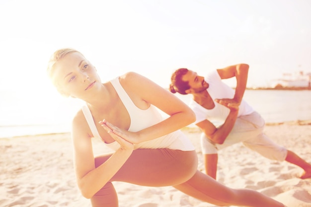 fitness, sport, vriendschap en lifestyle concept - close-up van een paar dat yoga-oefeningen maakt op het strand